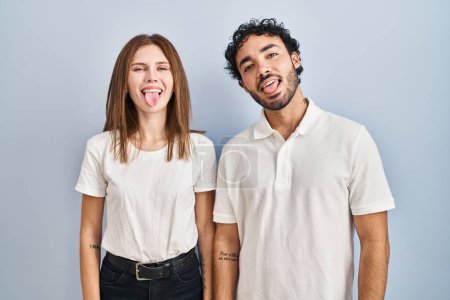Photo for Young couple wearing casual clothes standing together sticking tongue out happy with funny expression. emotion concept. - Royalty Free Image