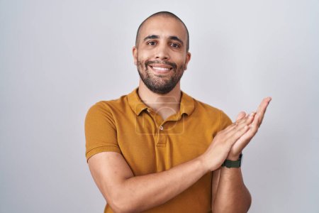 Téléchargez les photos : Homme hispanique avec barbe debout sur fond blanc applaudissements heureux et joyeux, souriant mains fières ensemble - en image libre de droit