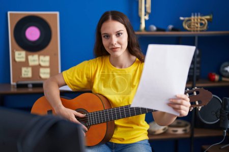 Photo for Young woman musician playing classical guitar at music studio - Royalty Free Image