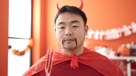 Téléchargez les photos : Young chinese man wearing devil costume holding trident at home - en image libre de droit