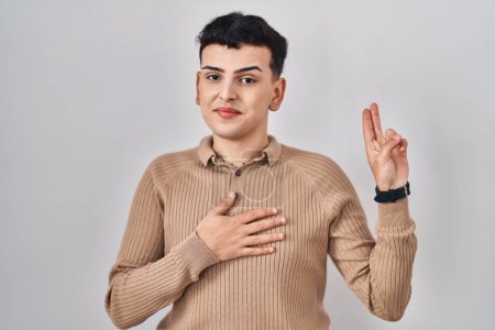 Photo for Non binary person standing over isolated background smiling swearing with hand on chest and fingers up, making a loyalty promise oath - Royalty Free Image