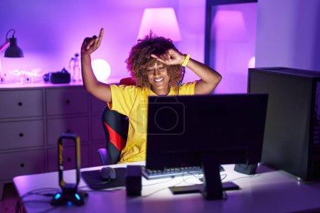 Foto de Mujer afroamericana streamer jugando videojuego con la expresión ganadora en la sala de juegos - Imagen libre de derechos