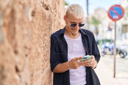 Téléchargez les photos : Jeune homme caucasien souriant confiant en utilisant un smartphone à la rue - en image libre de droit