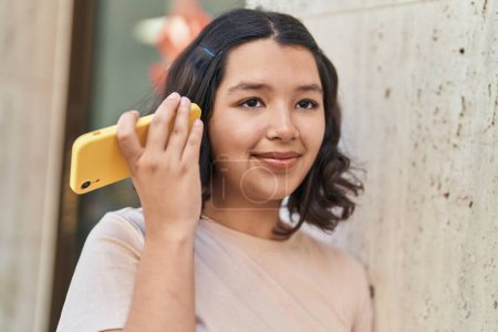 Téléchargez les photos : Young woman smiling confident listening audio message by the smartphone at street - en image libre de droit