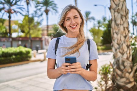 Téléchargez les photos : Jeune femme blonde souriante confiante en utilisant un smartphone au parc - en image libre de droit