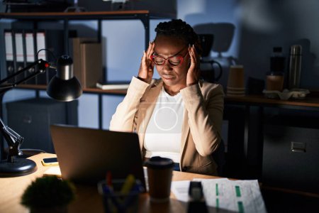 Photo for Beautiful black woman working at the office at night with hand on head for pain in head because stress. suffering migraine. - Royalty Free Image