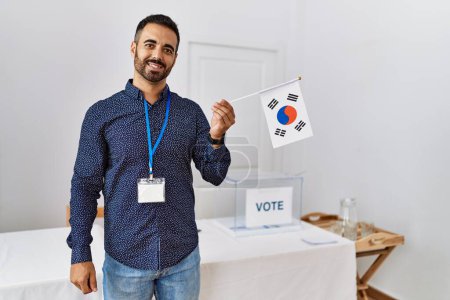 Photo for Young hispanic man smiling confident holding korea flag standing at electoral college - Royalty Free Image