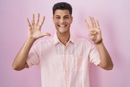 Téléchargez les photos : Jeune homme hispanique debout sur fond rose montrant et pointant vers le haut avec les doigts numéro neuf tout en souriant confiant et heureux. - en image libre de droit