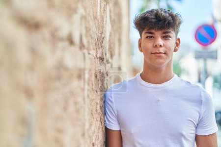 Foto de Joven adolescente hispano sonriendo confiado de pie en la calle - Imagen libre de derechos