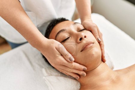 Photo for Young hispanic woman having facial massage at beauty center - Royalty Free Image