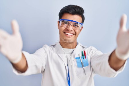 Téléchargez les photos : Hispanic man working as scientist looking at the camera smiling with open arms for hug. cheerful expression embracing happiness. - en image libre de droit