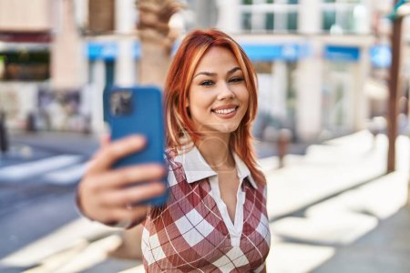Téléchargez les photos : Jeune femme caucasienne souriant confiant faire selfie par le smartphone à la rue - en image libre de droit