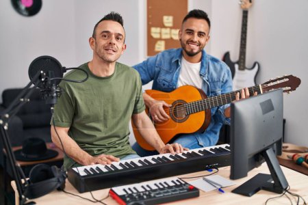 Foto de Two men musicians playing piano and classical guitar at music studio - Imagen libre de derechos