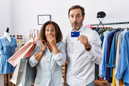 Photo for Hispanic middle age couple holding shopping bags and credit card shocked covering mouth with hands for mistake. secret concept. - Royalty Free Image