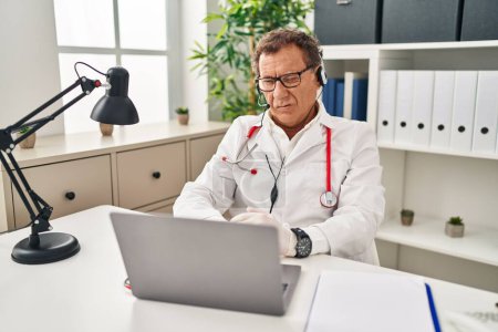 Photo for Senior doctor man working on online appointment winking looking at the camera with sexy expression, cheerful and happy face. - Royalty Free Image