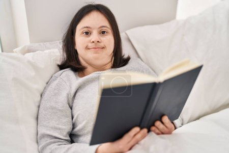 Téléchargez les photos : Jeune femme avec duvet livre de lecture couché sur le lit dans la chambre - en image libre de droit