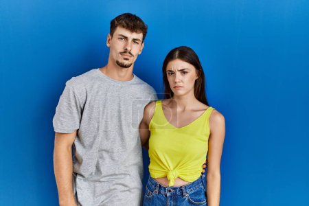 Foto de Young hispanic couple standing together over blue background depressed and worry for distress, crying angry and afraid. sad expression. - Imagen libre de derechos