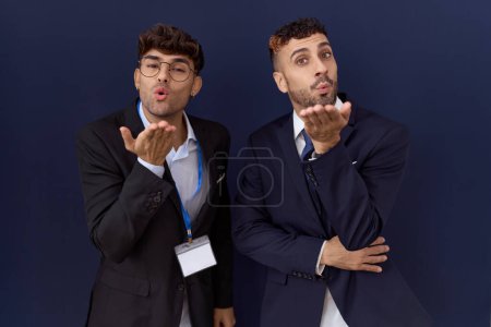 Téléchargez les photos : Two hispanic business men wearing business clothes looking at the camera blowing a kiss with hand on air being lovely and sexy. love expression. - en image libre de droit