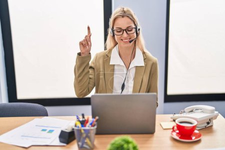 Photo for Young caucasian woman working wearing call center agent headset smiling with an idea or question pointing finger with happy face, number one - Royalty Free Image