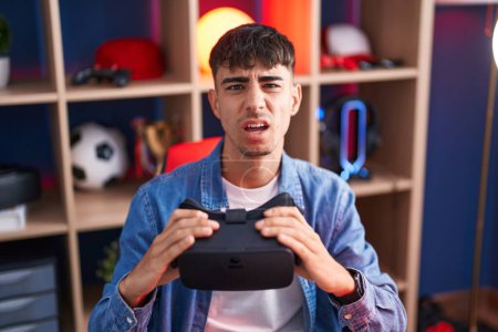 Photo for Young hispanic man wearing virtual reality glasses clueless and confused expression. doubt concept. - Royalty Free Image