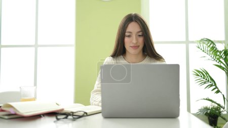 Téléchargez les photos : Jeune belle étudiante hispanique utilisant un ordinateur portable étudiant à la maison - en image libre de droit