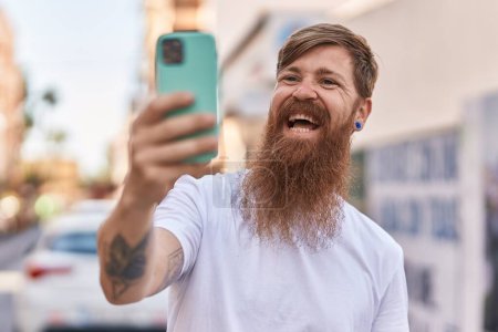Photo for Young redhead man smiling confident making selfie by the smartphone at street - Royalty Free Image