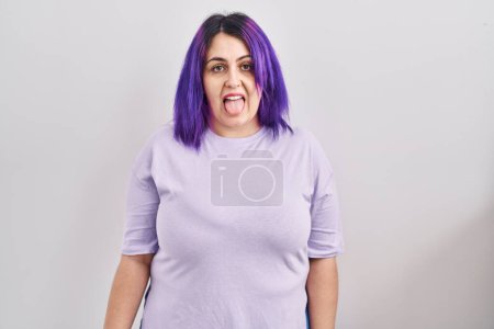 Téléchargez les photos : Plus size woman wit purple hair standing over isolated background sticking tongue out happy with funny expression. emotion concept. - en image libre de droit