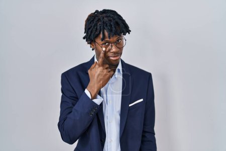 Téléchargez les photos : Jeune homme africain avec dreadlocks veste d'affaires sur fond blanc pointant vers l'oeil vous regarder geste, expression suspecte - en image libre de droit