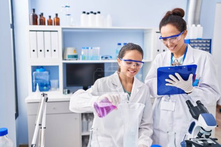 Foto de Woman and girl wearing scientist uniform working at laboratory - Imagen libre de derechos