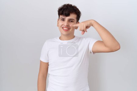 Téléchargez les photos : Young non binary man wearing casual white t shirt pointing with hand finger to face and nose, smiling cheerful. beauty concept - en image libre de droit