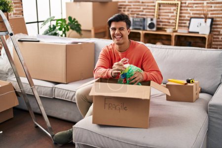 Photo for Hispanic man moving to a new home unpacking winking looking at the camera with sexy expression, cheerful and happy face. - Royalty Free Image