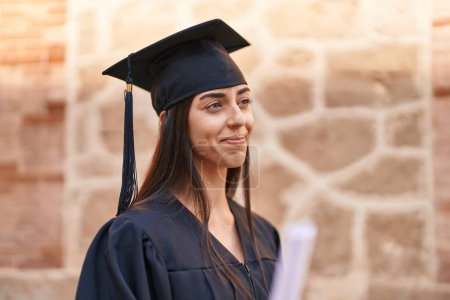 Photo for Young hispanic woman wearing graduated uniform standing at university - Royalty Free Image