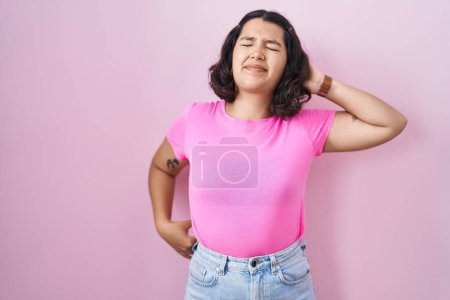 Photo for Young hispanic woman standing over pink background suffering of neck ache injury, touching neck with hand, muscular pain - Royalty Free Image