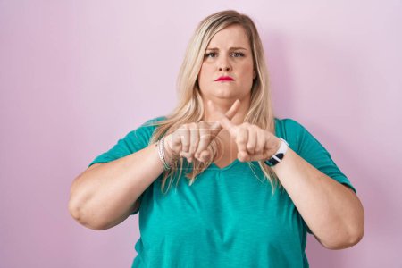 Téléchargez les photos : Caucasien plus taille femme debout sur fond rose expression de rejet croisement doigts faisant signe négatif - en image libre de droit