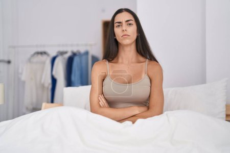 Foto de Young brunette woman in the bed at home skeptic and nervous, disapproving expression on face with crossed arms. negative person. - Imagen libre de derechos