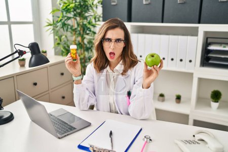 Photo for Young woman working at dietitian clinic in shock face, looking skeptical and sarcastic, surprised with open mouth - Royalty Free Image