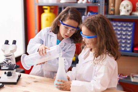 Foto de Two kids students pouring liquid on test tube at laboratory classroom - Imagen libre de derechos