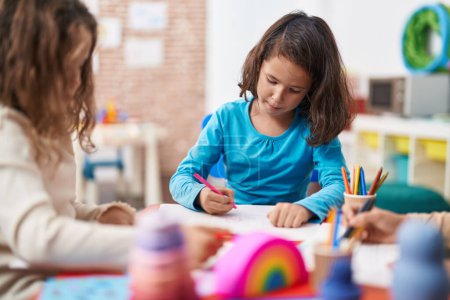 Foto de Dos niños preescolares sentados en la mesa dibujando en papel en el jardín de infantes - Imagen libre de derechos