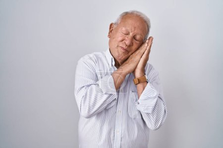 Photo for Senior man with grey hair standing over isolated background sleeping tired dreaming and posing with hands together while smiling with closed eyes. - Royalty Free Image