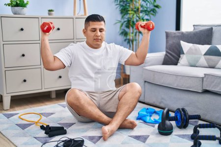 Photo for Young latin man using dumbbells training at home - Royalty Free Image