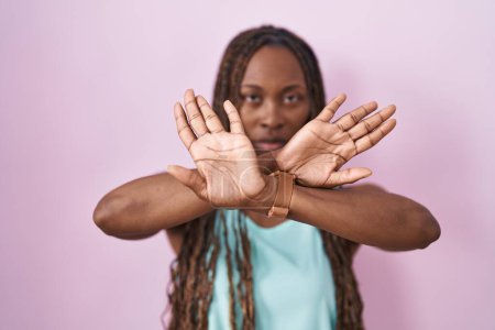 Téléchargez les photos : African american woman standing over pink background rejection expression crossing arms and palms doing negative sign, angry face - en image libre de droit