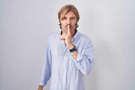 Téléchargez les photos : Homme caucasien avec moustache debout sur fond blanc demandant à être calme avec le doigt sur les lèvres. silence et concept secret. - en image libre de droit