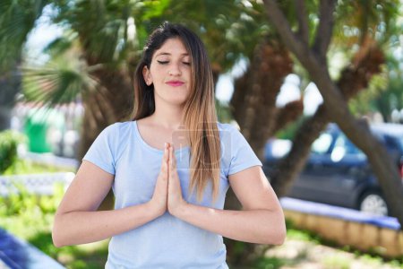 Téléchargez les photos : Jeune femme hispanique souriant confiant faire de l'exercice de yoga au parc - en image libre de droit