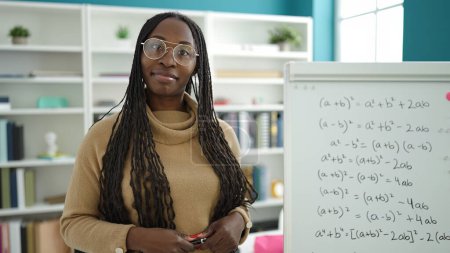 Téléchargez les photos : Femme africaine souriante confiante par tableau magnétique maths à l'université de la bibliothèque - en image libre de droit