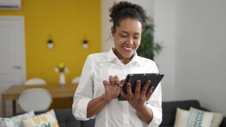 Téléchargez les photos : African american woman smiling confident using touchpad at home - en image libre de droit