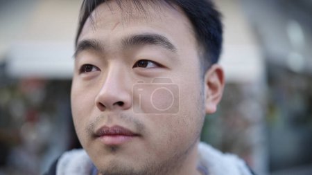 Téléchargez les photos : Jeune homme chinois regardant vers le côté avec une expression sérieuse à la rue - en image libre de droit