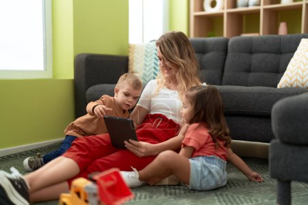 Téléchargez les photos : Woman with girl and boy using touchpad sitting on floor at home - en image libre de droit