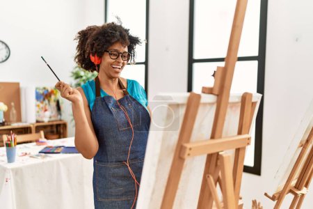 Foto de Joven afroamericana mujer escuchando música dibujo en el estudio de arte - Imagen libre de derechos
