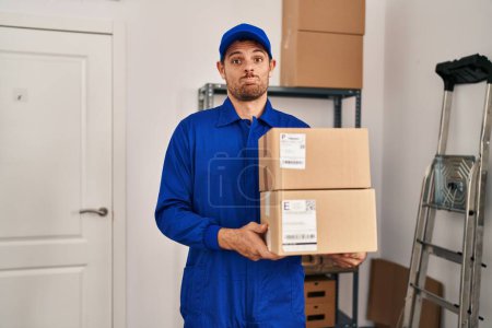 Photo for Young hispanic man working on moving service holding boxes depressed and worry for distress, crying angry and afraid. sad expression. - Royalty Free Image