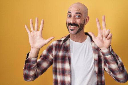 Téléchargez les photos : Homme hispanique avec barbe debout sur fond jaune montrant et pointant vers le haut avec les doigts numéro huit tout en souriant confiant et heureux. - en image libre de droit